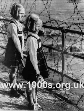 Barbed wire preventing wartime children playing on a beach