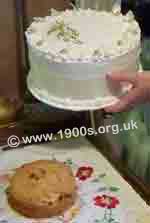 Decorated cardboard cake cover lifts to reveal a smallr cake in WW2