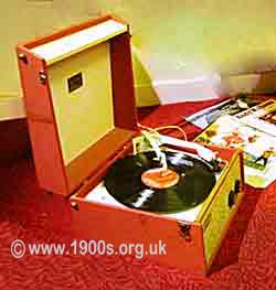 Record player from 1950s, UK, portable and housed in a box with a handle and latched lid.