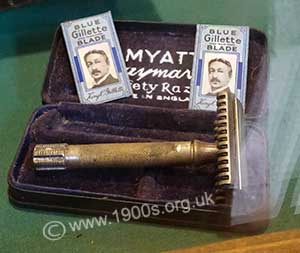 Early safety razor in its case with two spare razor blades wrapped by Gillette