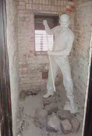 Life-size model of a vagrant breaking rocks in the work area behind his cell in a casual ward (also known as a dosshouse).