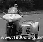 A man from the AA (Automobile Association) in the 1940s or 1950s, arriving by motor bike and sidecar to help motoring AA members in difficulty.