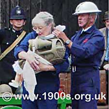 WW2 ARP warden carrying a baby in a baby's gas mask