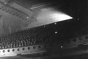 Light from the projector in an old cinema showing up in the dusty air above the audience's heads.