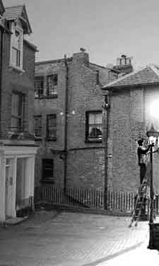 Lamplighter, early to mid 1900s England, lighting a pilot light streetlamp by turning on the gas with a pole.