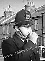 Policeman blowing his police whistle to bring assistance from nearby policemen, mid-1900s