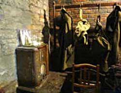 Room off the corridor of the WW2 public shelters under the battlements of Cardiff Castle showing candles, a radio and clothes, small image