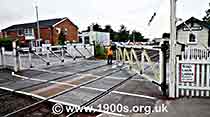 Railway worker opening the gates for trains of an old-style manual level crossing so closing them to road traffic, thumbnail