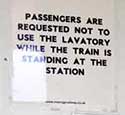 Notice inside the toilet of an old train, requesting passengers to refrain from using the toilet while the train is in a station.