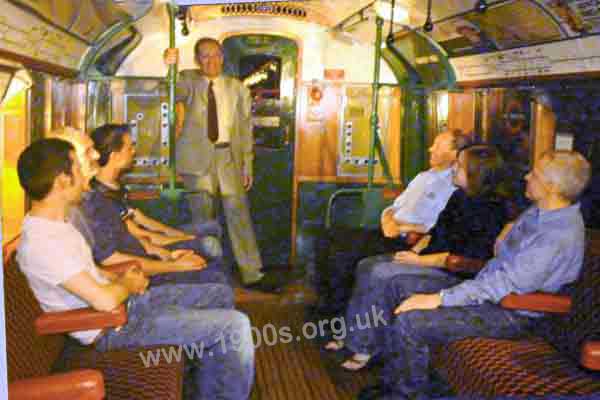 Inside an old tube train showing the hanging ball-style grips and a man gripping a support pole