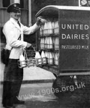 Milkman's uniform, mid 1900: black peaked hat, white overall, leather shoulder coin bag and the protective apron.