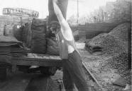 A coalman loading sacks of coal onto a lorry 