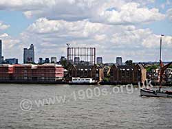 View across the Thames at London docklands showing the shell of an old gasometer.