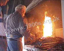 Blacksmith heating iron rod in his fire