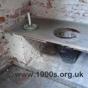 inside a privy showing the wooden seat and the bucket underneath