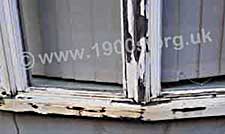 Flaking paintwork on rotting wooden windows