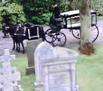 Victorian/Edwardian hearse leaving a cemetery after delivering a coffin