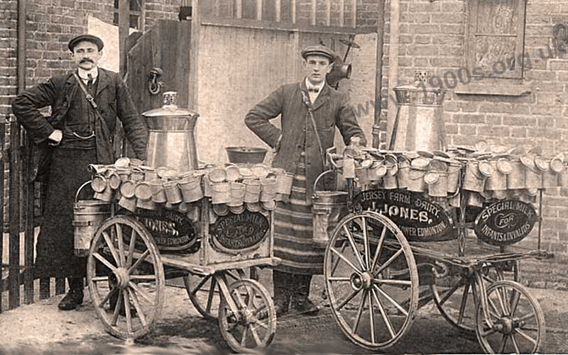 Milk delivery hand carts with jugs and milk churns - with the dairy owner John Jones and his assistant, early 1900s.