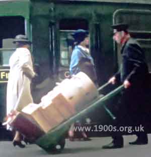 Station platform porter carrying luggage on his trolley in expectation of a tip