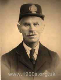Front view of an early 1900s postman showing his uniquely shaped hat.