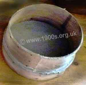 Old flour sieve with metal mesh secured with thin untreated wood which acted as the handle.